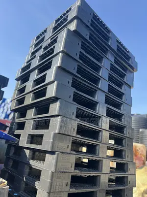 Tall Stack Of Black Plastic Pallets.