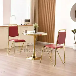 Modern Round Dining Table With a Gold Base and Two Red and Gold Chairs