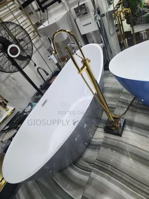 Bathtub Paired With a Gold Floor-Mounted Filler Faucet and Hand Shower