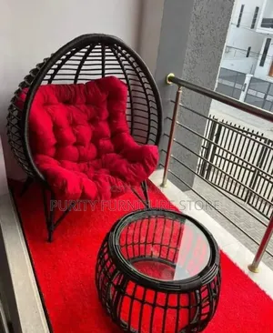 This Is a Black Rattan Egg-Shaped Chair With a Red Cushion.