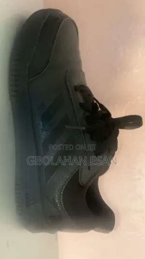 A Pair of White Shoes and a Pair of Adidas Tensuar Sport Black