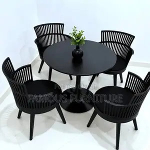 The Image Shows a Black Round Dining Table Set With Four Matching