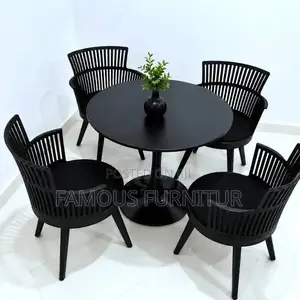 The Image Shows a Black Round Dining Table Set With Four Matching